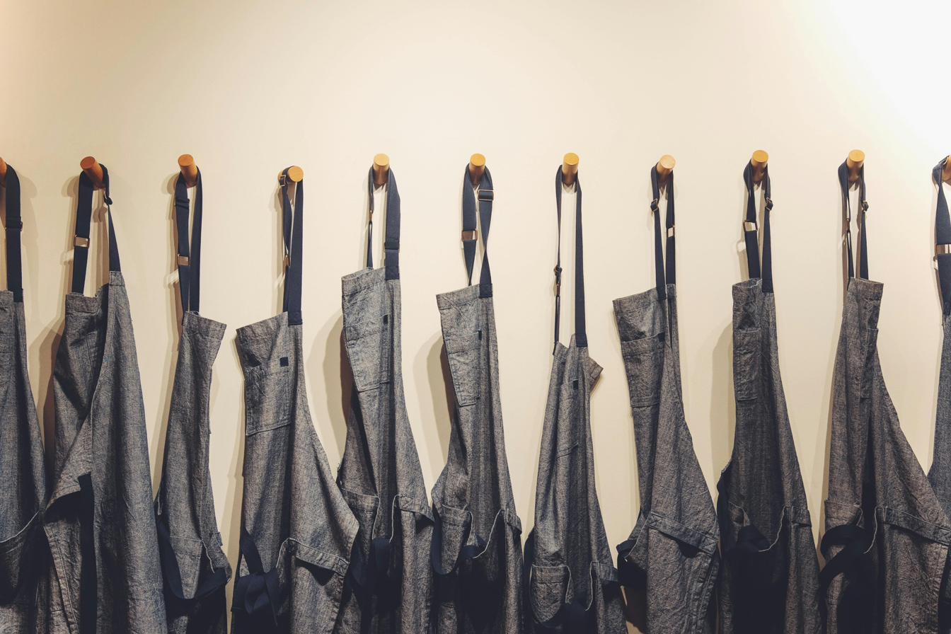 Row of grey aprons hanging on pegs in a hospitality setting